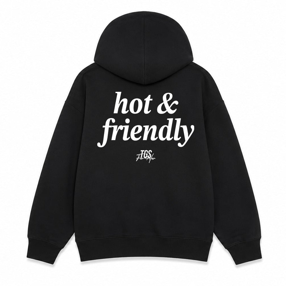 Black pullover hoodie shown from the front and back on a plain white background. The front has a small white 'hot & friendly' logo on the left chest, and the back has a large white 'hot & friendly' logo with a smaller 'TSG' mark below.