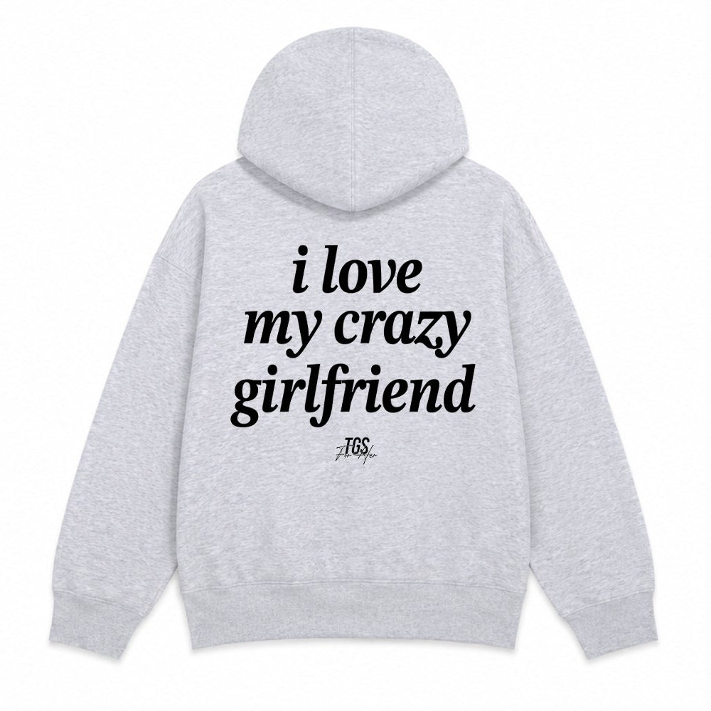 A light heather gray pullover hoodie shown from both the front and back. The front features a small black text graphic on the left chest reading 'i love my crazy girlfriend'.